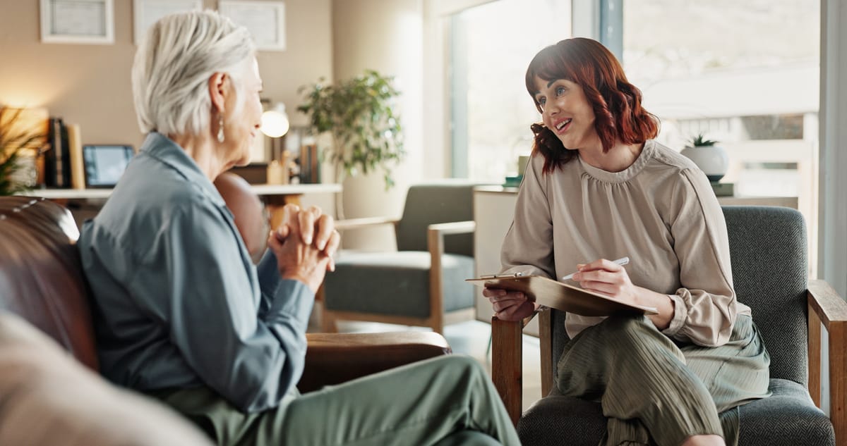 Psychologist chats with senior woman in consultation.