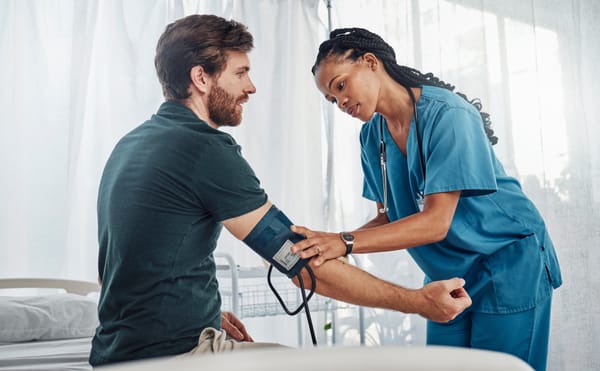 Female nurse taking man's blood pressure in doctor's office.